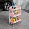 A pink 3-tier rolling metal storage cart filled with various tools and supplies, including a drill and coiled wire.