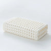 A rectangular white waffle weave bath towel folded neatly on a white surface.