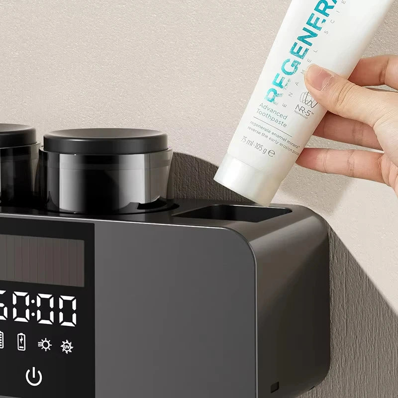 Una mano sostiene un tubo de pasta dental Regenerate Advanced y un dispositivo esterilizador de cepillos montado en la pared.