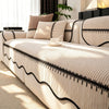 A beige striped chenille sofa cover with a black pleated hem resting on a light-colored sofa.