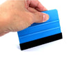 A hand is holding a blue suede felt squeegee with a black rubber blade for vinyl wrap and window tint installation.
