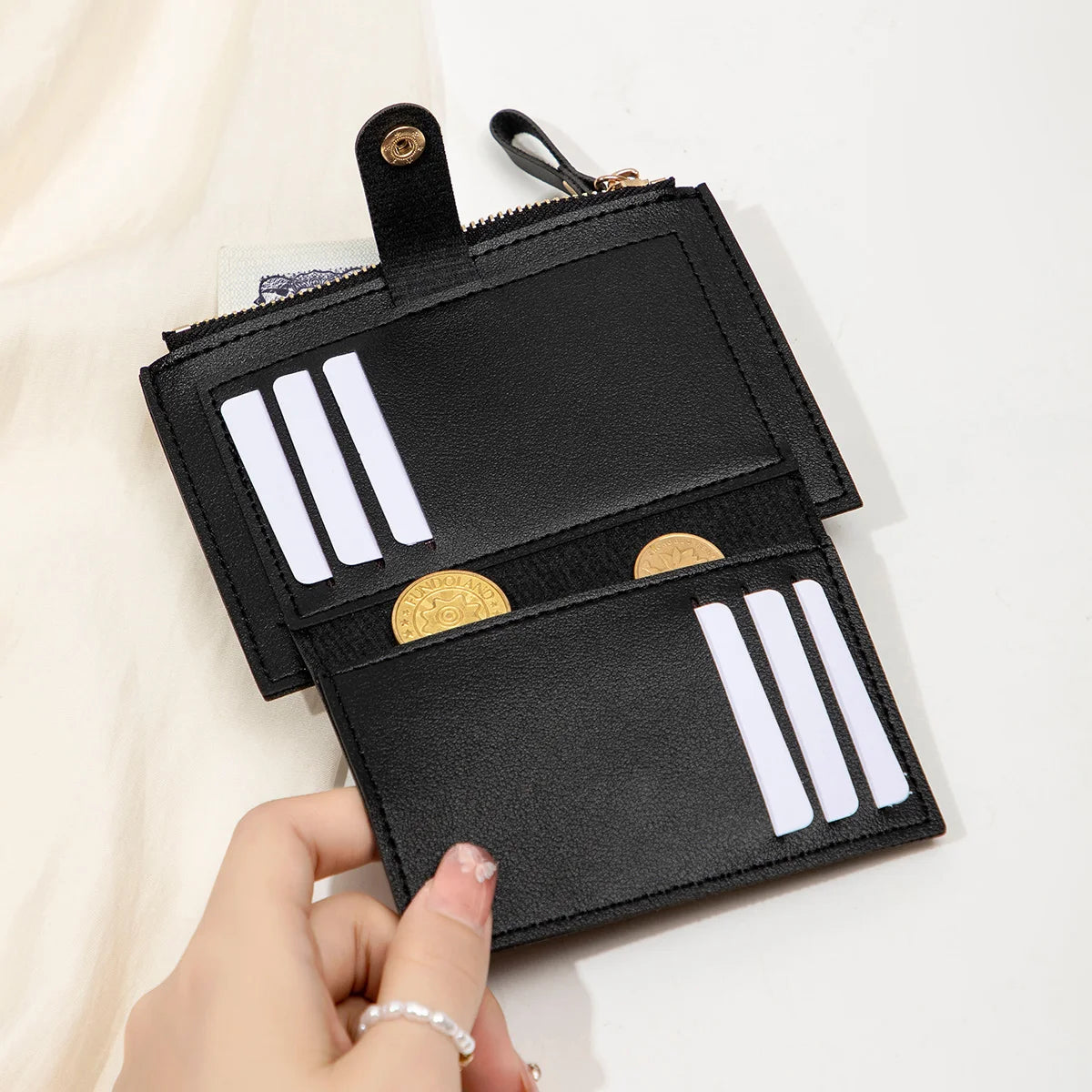 A black slim PU leather card holder wallet with silver stripes and gold accents is being held by a hand.