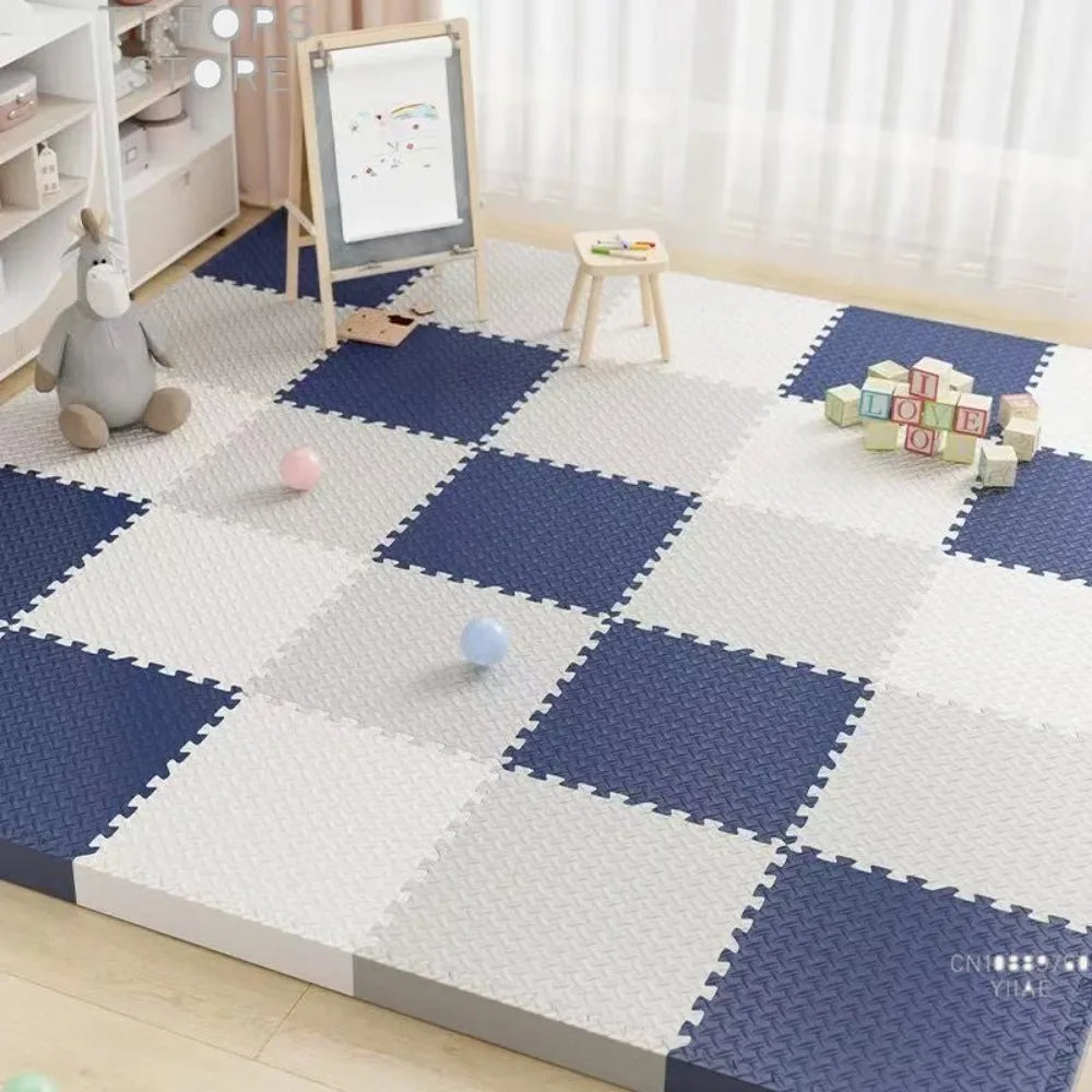 A blue and white interlocking foam play mat with various toys and a wooden stool in a bright room.