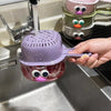 A hand holds a purple fruit washing basket with a pink lid and a clear base, next to stacked green and pink baskets in a kitc