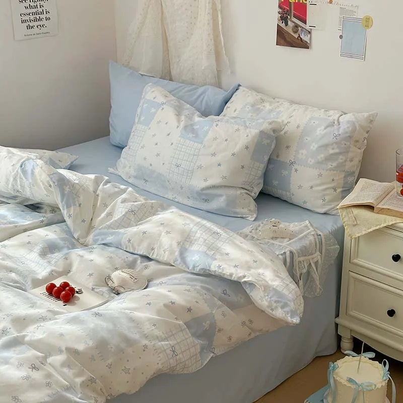 A light blue duvet cover set with white floral patterns and two matching pillowcases displayed on a bed.