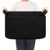 A person holds a black woven cotton rope storage basket with handles.