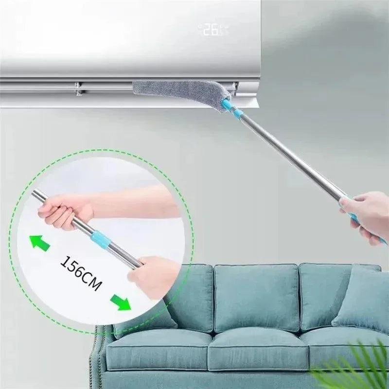 A hand is using a telescopic microfiber duster brush with an adjustable handle to clean a white appliance.