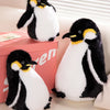 A black and white penguin plush toy sitting next to a pink box.