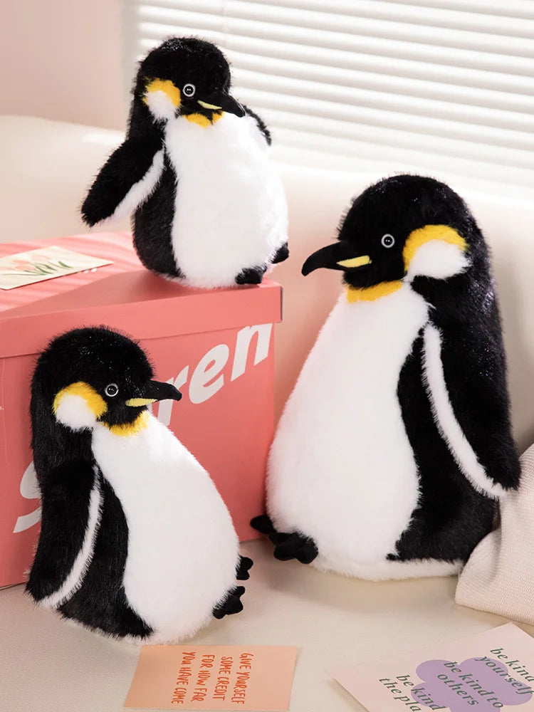 A black and white penguin plush toy sitting next to a pink box.