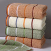 A stack of brown and green bath towels with striped accents, showing a set of premium cotton towels.