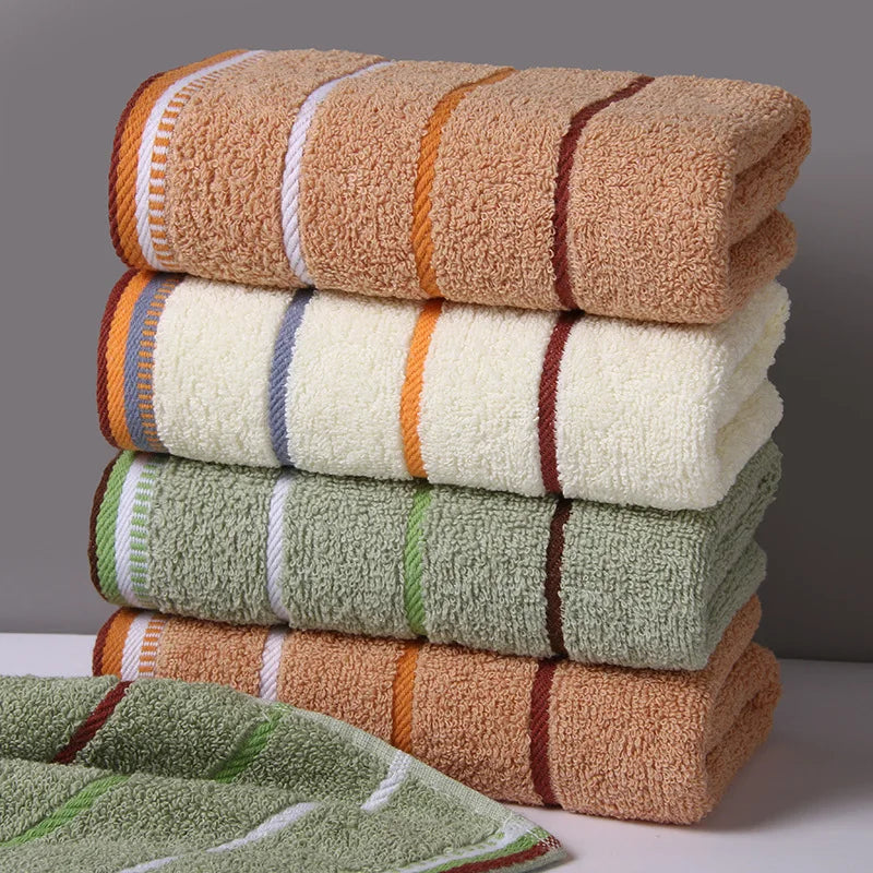 A stack of brown and green bath towels with striped accents, showing a set of premium cotton towels.