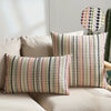 A set of two bohemian linen pillow covers featuring a multicolored geometric pattern on a light beige sofa.