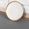 A round white plate with a gold rim resting on a wooden surface.