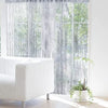 A sheer silver tassel string curtain hangs in a window, filtering natural light and creating a soft, textured drape.