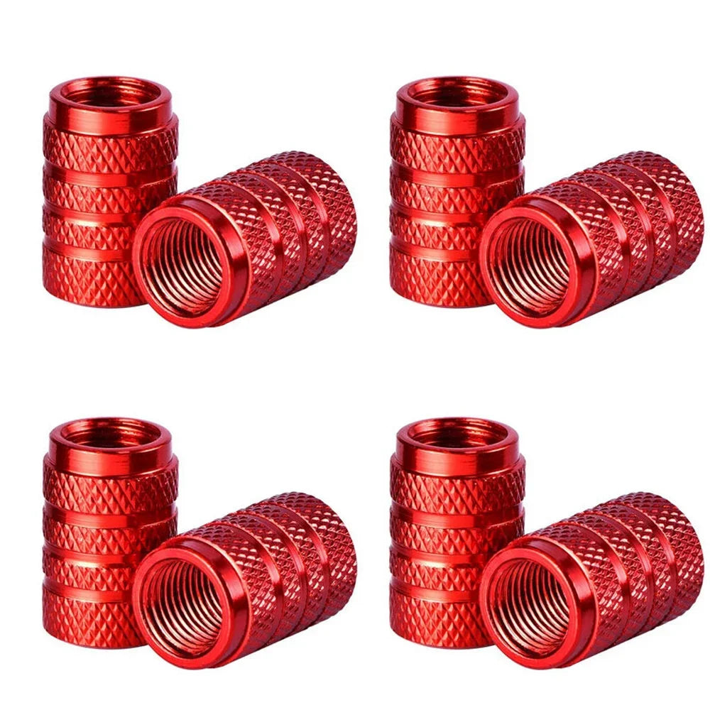 A set of four knurled red aluminum tire valve caps shown in various angles.