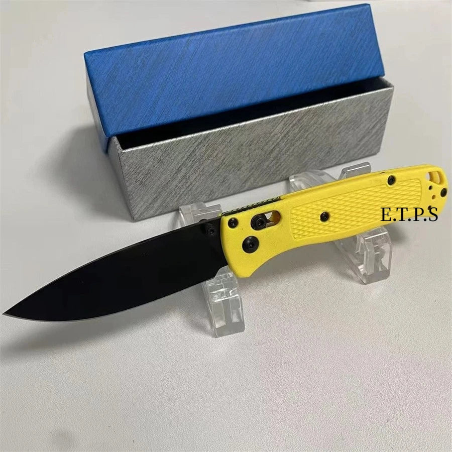 A yellow folding pocket knife with a black blade is displayed next to its silver and blue packaging box.