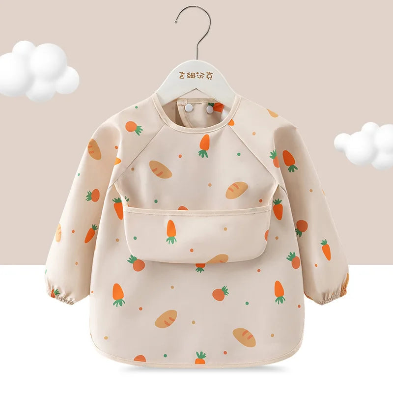 A beige children's waterproof long sleeve feeding bib with a catch pocket decorated with various fruit shapes.