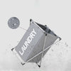 A gray foldable laundry basket is shown with water droplets splashing around it.
