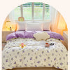 Lavendelfarziges Blumen-Duvetcover auf einem Bett mit weißen Kissen und natürlichem Licht.