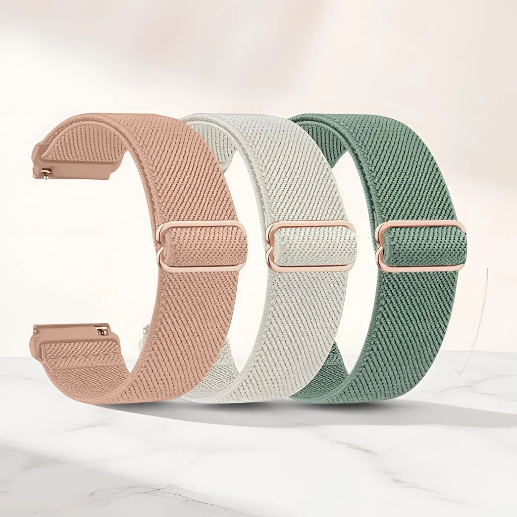 Tres bandas deportivas elásticas de colores rosa, beige y verde sobre una superficie de mármol blanco.