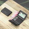 A black leather card holder wallet with multiple slots is displayed on a wooden surface.