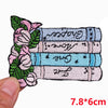 A set of embroidered iron-on patches featuring floral designs and text on a light blue fabric background.