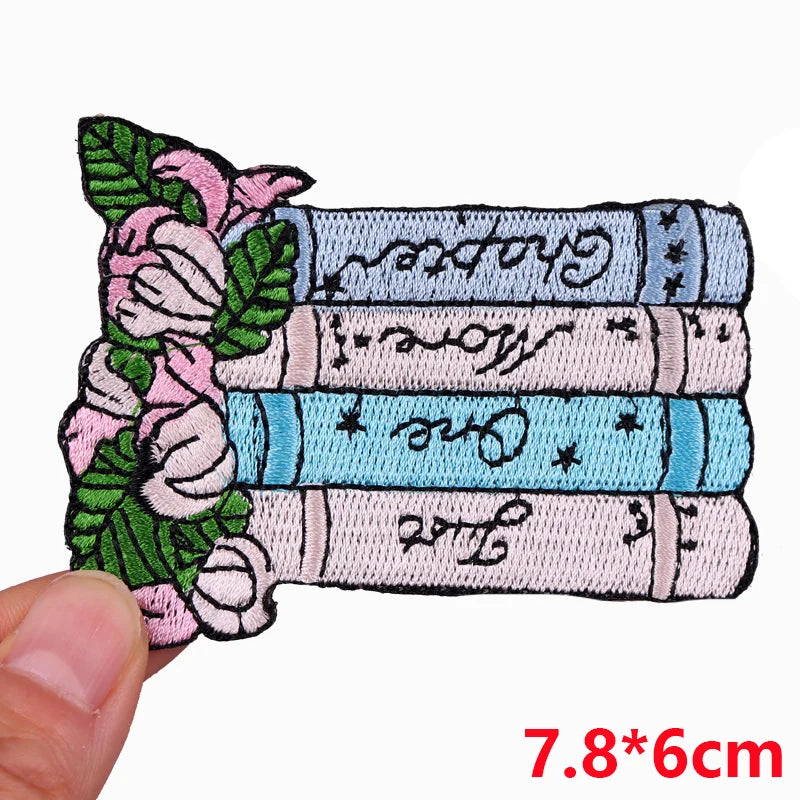 A set of embroidered iron-on patches featuring floral designs and text on a light blue fabric background.
