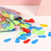 A pile of colorful plastic needle threaders in various shades of green, blue, and red scattered on a white surface.