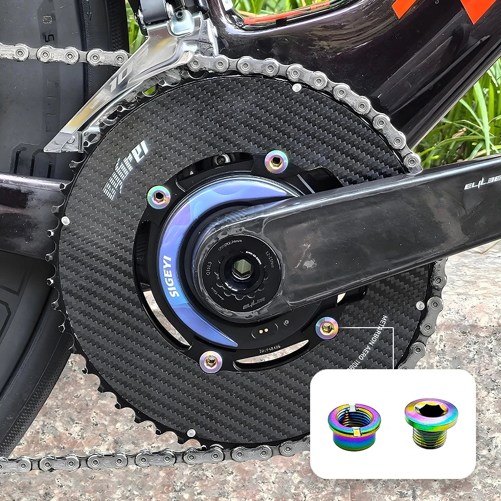 Close-up of a black carbon chainring with titanium alloy bolts and a silver chain visible on a bicycle.