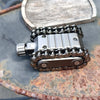 A close-up of a metal tactical tank fidget spinner with a rotating turret resting on a weathered metal surface.