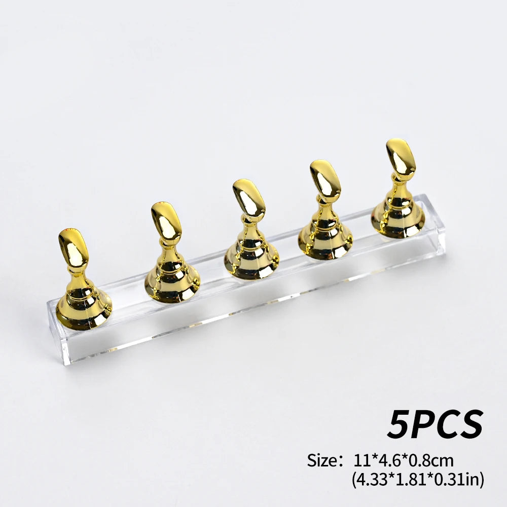 Five gold reusable nail glue clay pieces displayed on a clear acrylic surface.