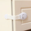 A white multi-purpose baby safety strap is attached to a cabinet door using a hook and strap.