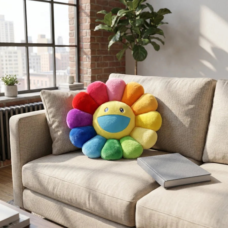 A cheerful sunflower plush cushion with a smiling face in various bright colors sits on a beige sofa.