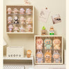 A wall-mounted display case holds various collectible dolls and figurines in an organized arrangement.