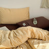 A set of minimalist striped 100% cotton duvet covers in yellow and beige tones.