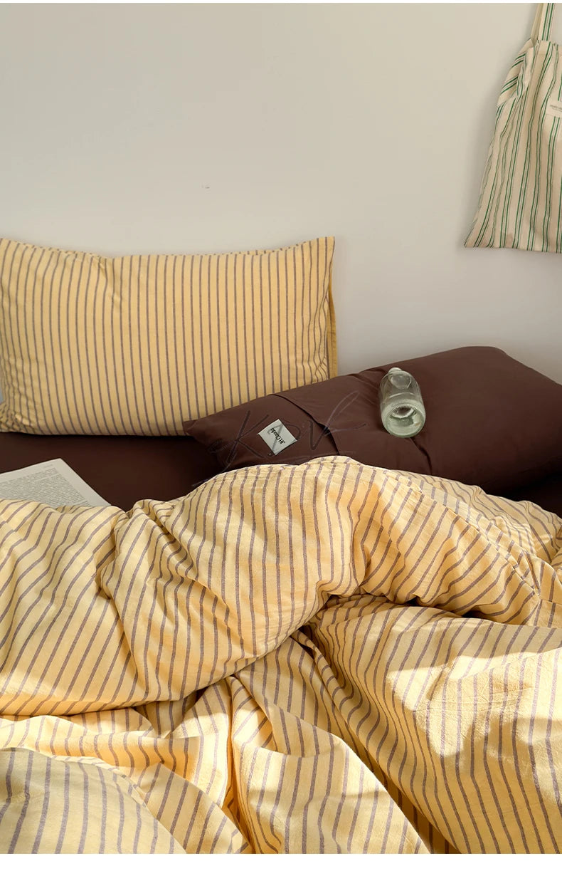 A set of minimalist striped 100% cotton duvet covers in yellow and beige tones.