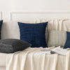 A set of four navy blue and gray corduroy throw pillow covers displayed on a light sofa.