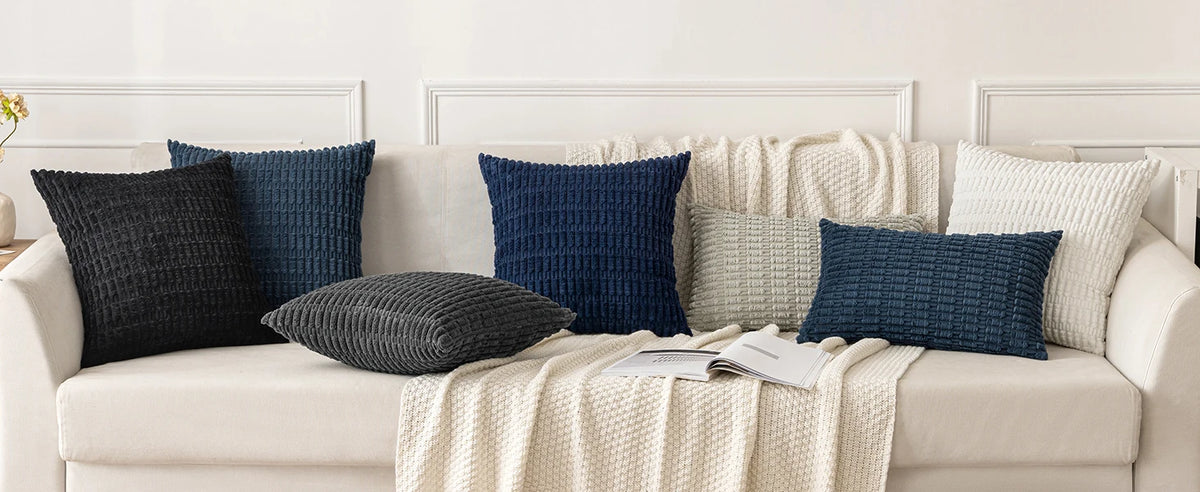 A set of four navy blue and gray corduroy throw pillow covers displayed on a light sofa.
