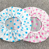 A pack of three disposable waterproof shower caps with polka dots in blue and pink on a gray background.