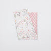 A white baby pillowcase featuring a pastel cartoon design with leaves and small animals, next to a pink patterned fabric.