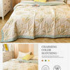 A beige patterned quilt is displayed on a bed, with laundry care symbols and fabric quality details shown below.