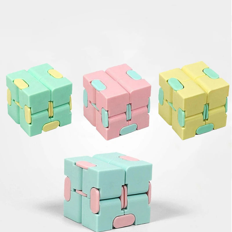 A set of colorful Infinity Magic Cube fidget toys in mint green, pink, and yellow.