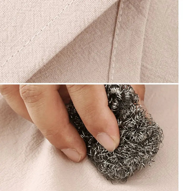 Close-up of a hand pulling a textured gray fabric from a light pink cotton kitchen apron.