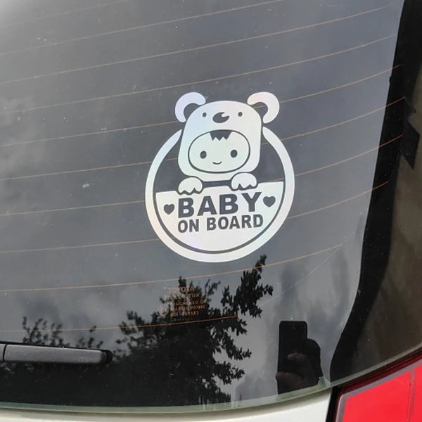 A circular decal featuring a cartoon bear and the text BABY ON BOARD on a dark car surface.