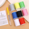 A collection of colorful spools of thread and a yellow sewing needle set are displayed on a beige surface.
