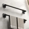 A black wall-mounted towel rack with a horizontal bar and two towel bars is installed on a light gray wall.