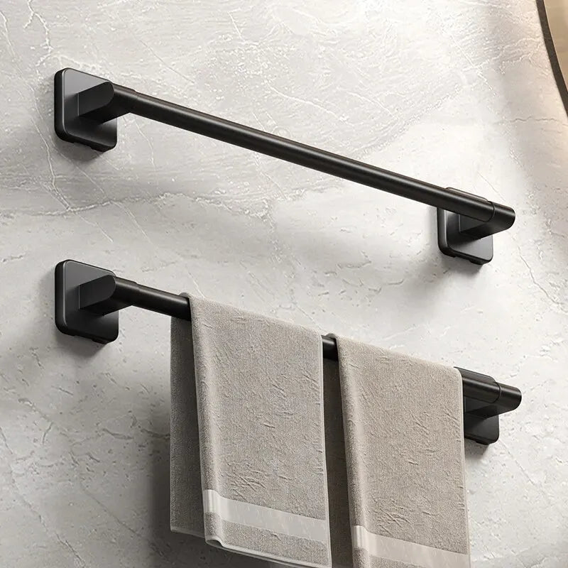 A black wall-mounted towel rack with a horizontal bar and two towel bars is installed on a light gray wall.