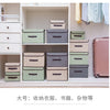 A set of fabric storage boxes in various shades of green, gray, and beige displayed on a white shelf.