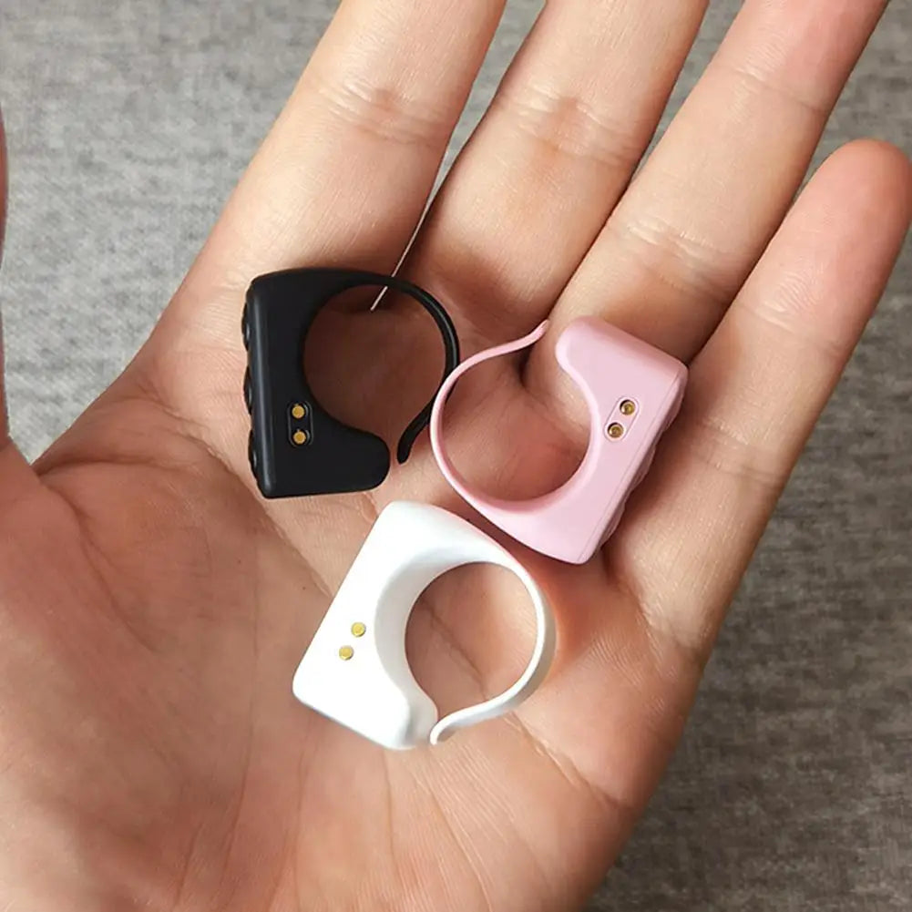 Three colored Bluetooth ring remote controls and a charging case are shown on a person's hand.
