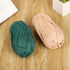 A ball of dark green soft T-shirt yarn for crochet and knitting resting on a wooden surface.